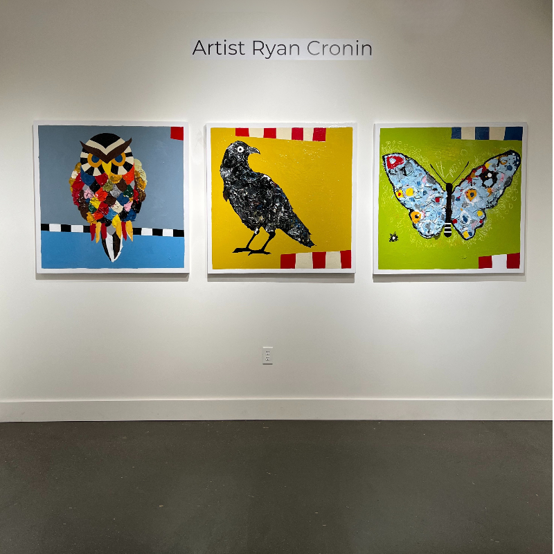 Three colorful artworks of an owl, a crow, and a butterfly by Artist Ryan Cronin on a wall.